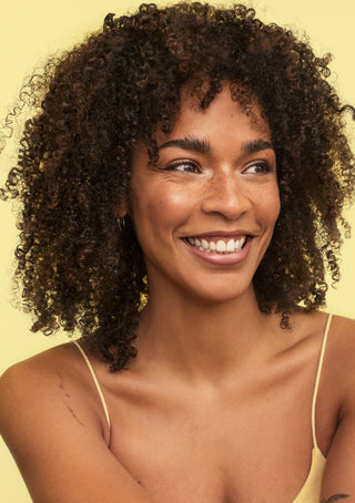Model with defined, bouncy curls after using BOUNCE.ME Curl Balm for hydration, shine, and frizz control.