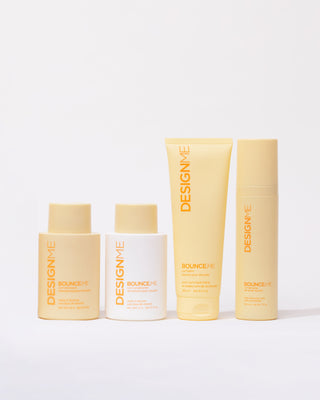 Front view of the 4 items Curl & Definition Bundle with yellow and white packaging, including shampoo, conditioner, curl balm, and spray gel.