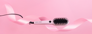 DESIGNME x DAFNI Smoothing Brush with a pink ribbon on a pink background.